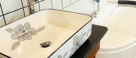 A bathroom with a white sink featuring a floral design and a bathtub.