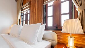 Una habitación de hotel con cama, mesita de noche, lámpara y ventana con cortinas.