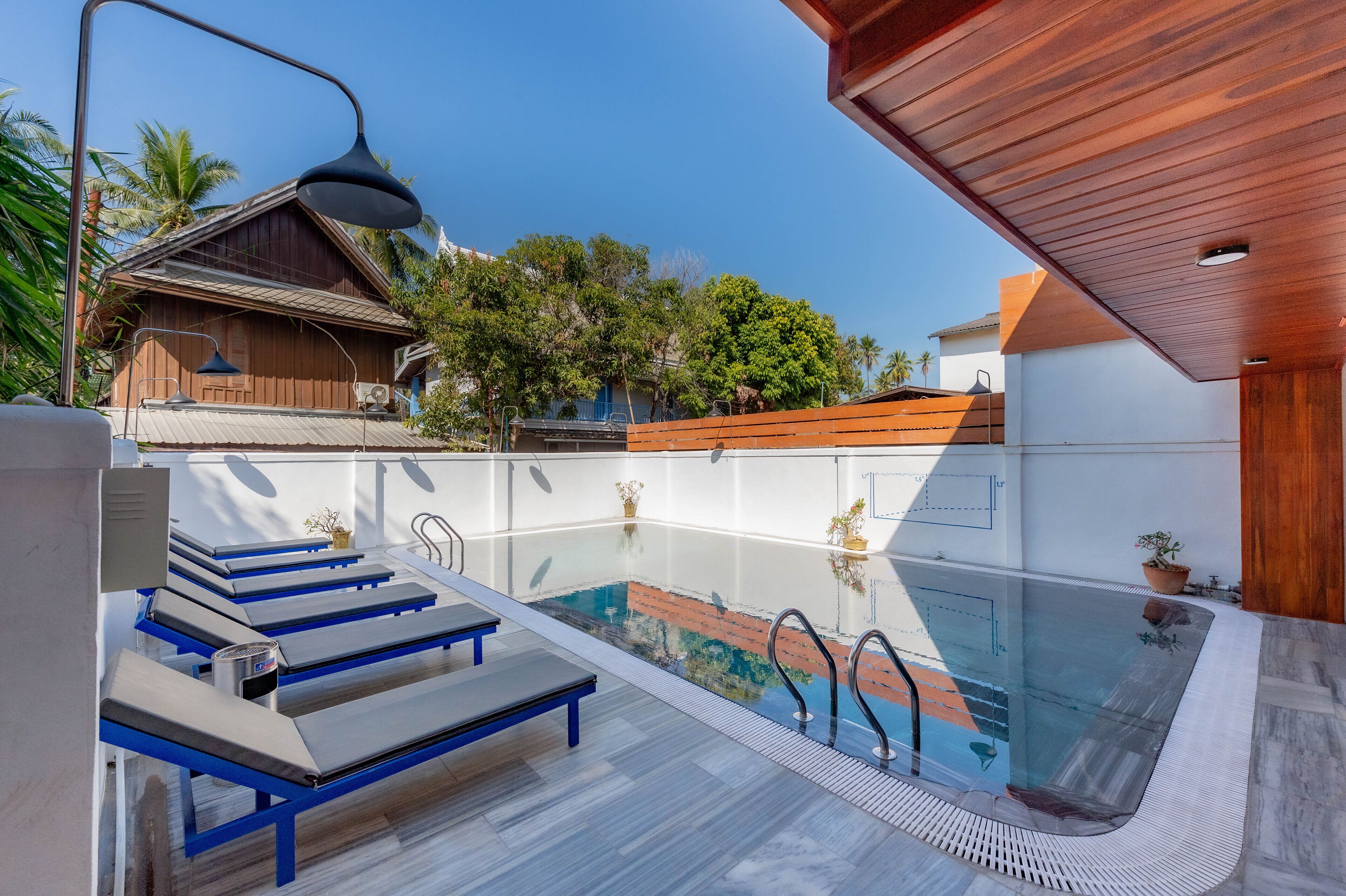 A modern outdoor pool area with lounge chairs and a wooden deck.
