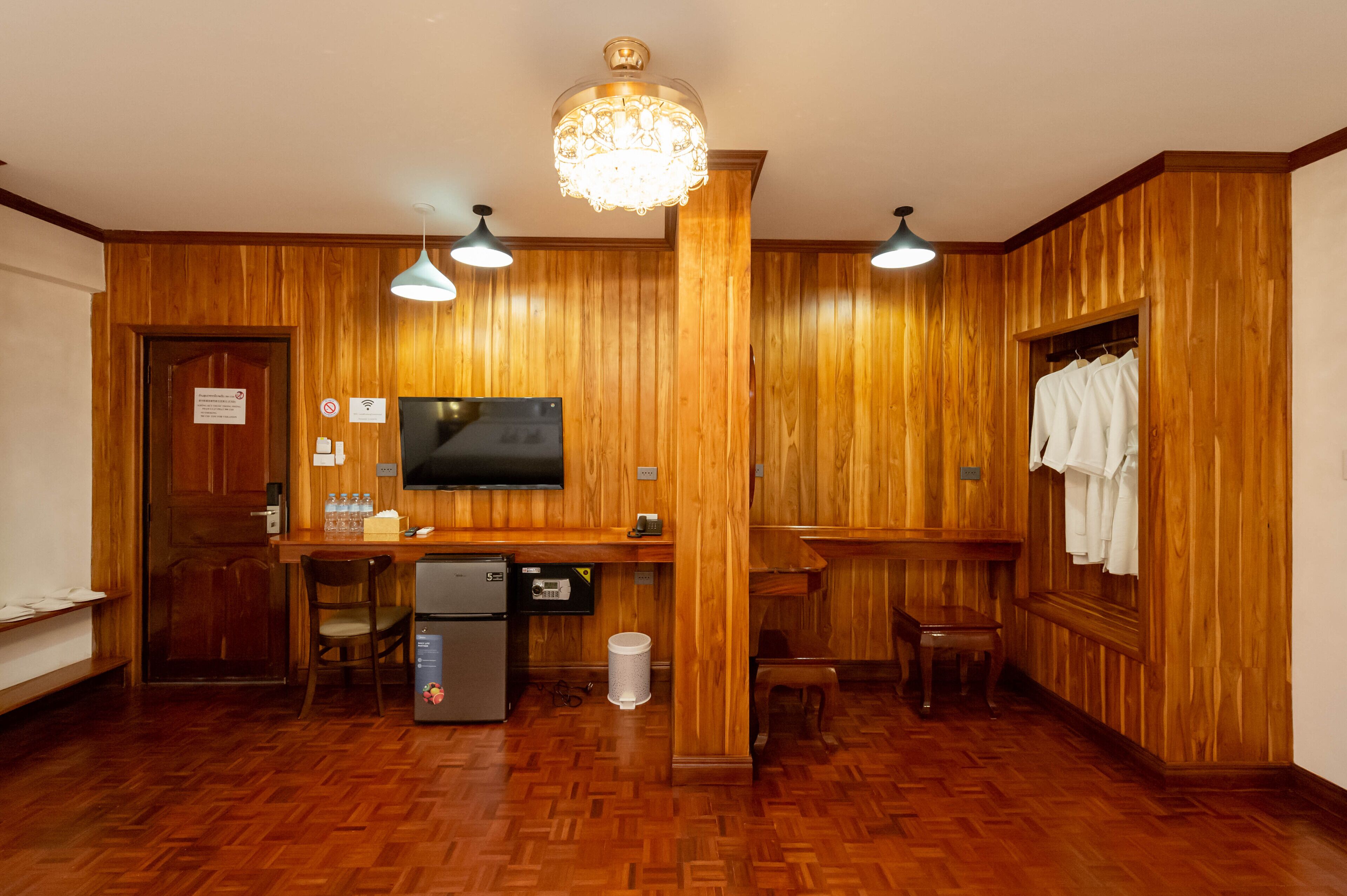 A wooden-paneled room with a television, refrigerator, and bench.