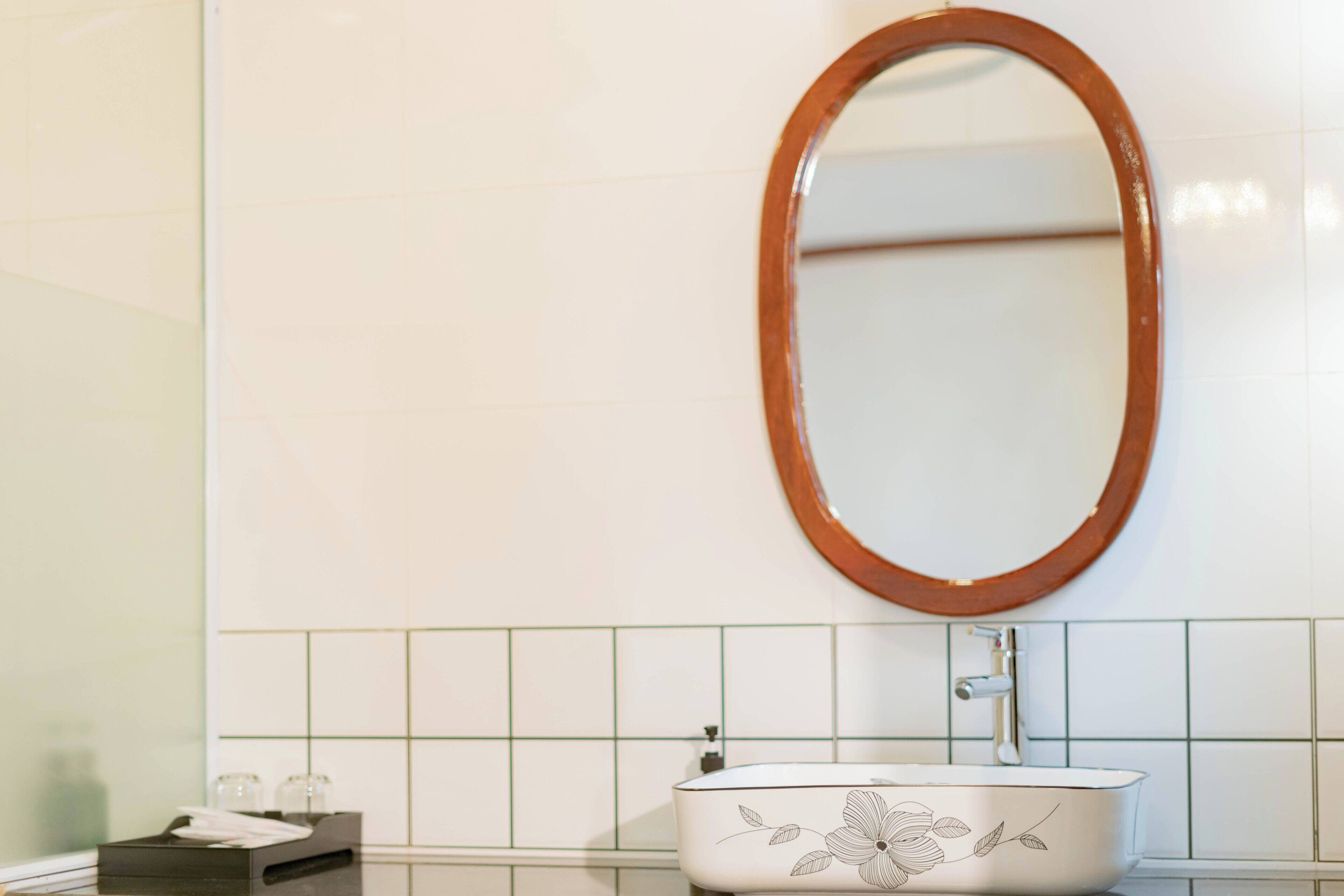 A bathroom with a white sink, a wooden-framed mirror, and a tissue box.