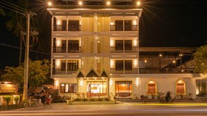 Un hotel de varios pisos con balcones, una entrada bien iluminada y un cartel.