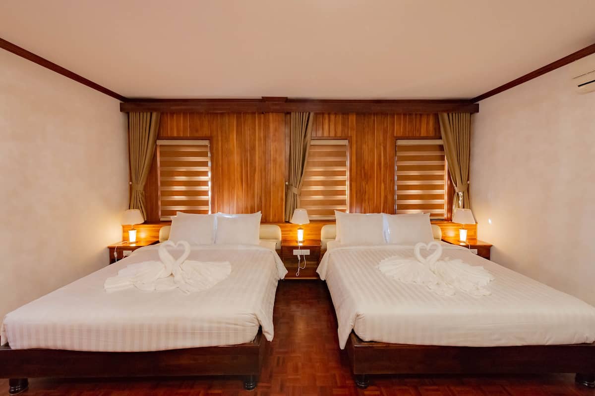 Une chambre d’hôtel avec deux lits, des têtes de lit en bois et des rideaux.