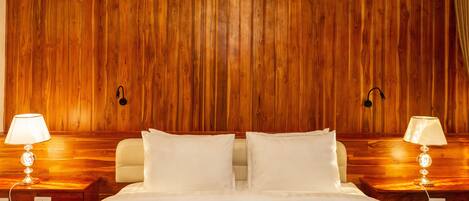 A hotel room with a wooden paneled wall, a bed with white bedding, and two bedside lamps.