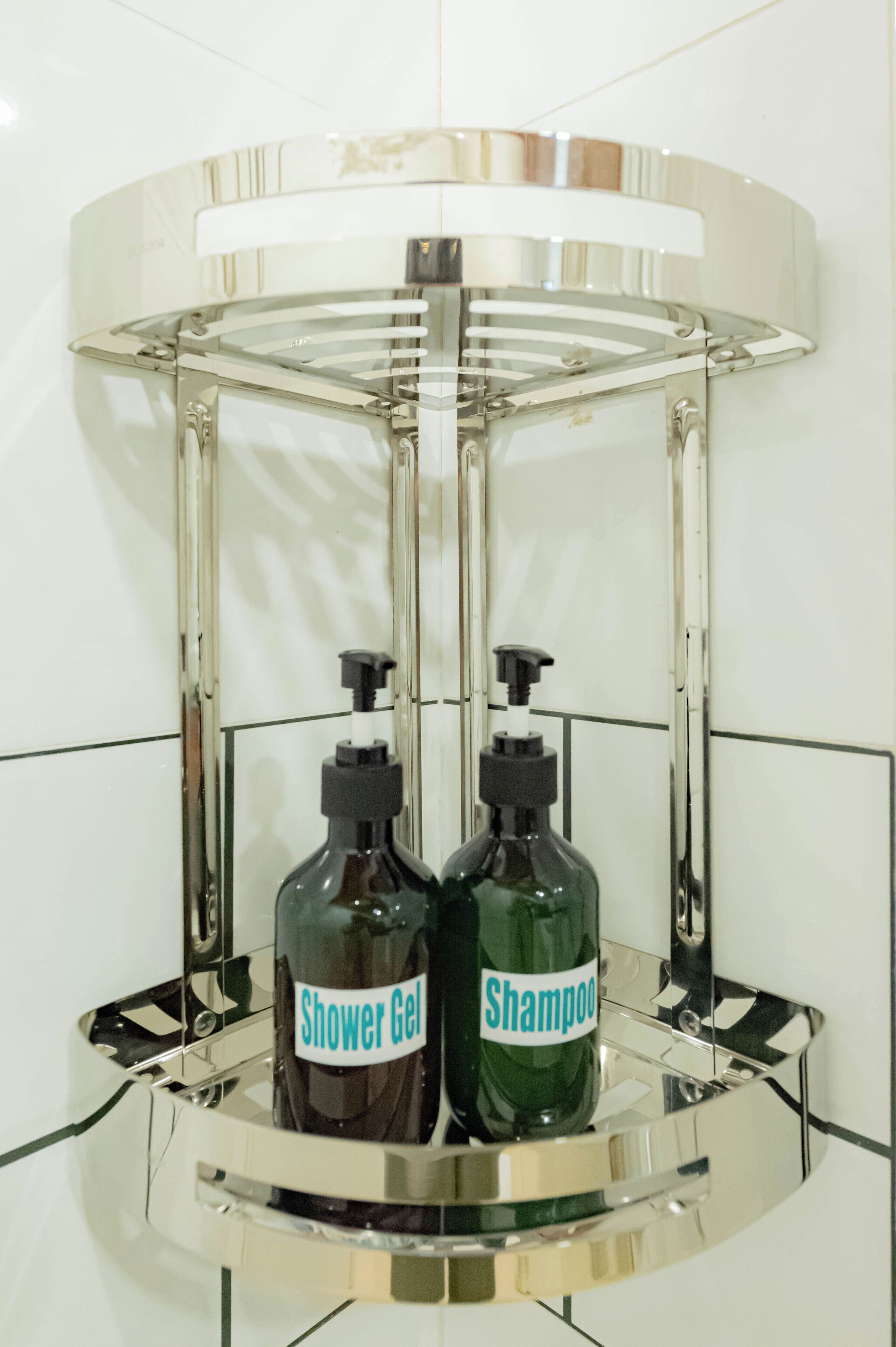 Un baño con lavamanos cromado y dos botellas de gel de ducha y champú.