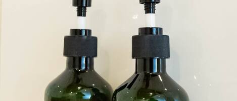 Two dark green bottles with pump dispensers, labeled "shower gel" and "shampoo" against a white background.