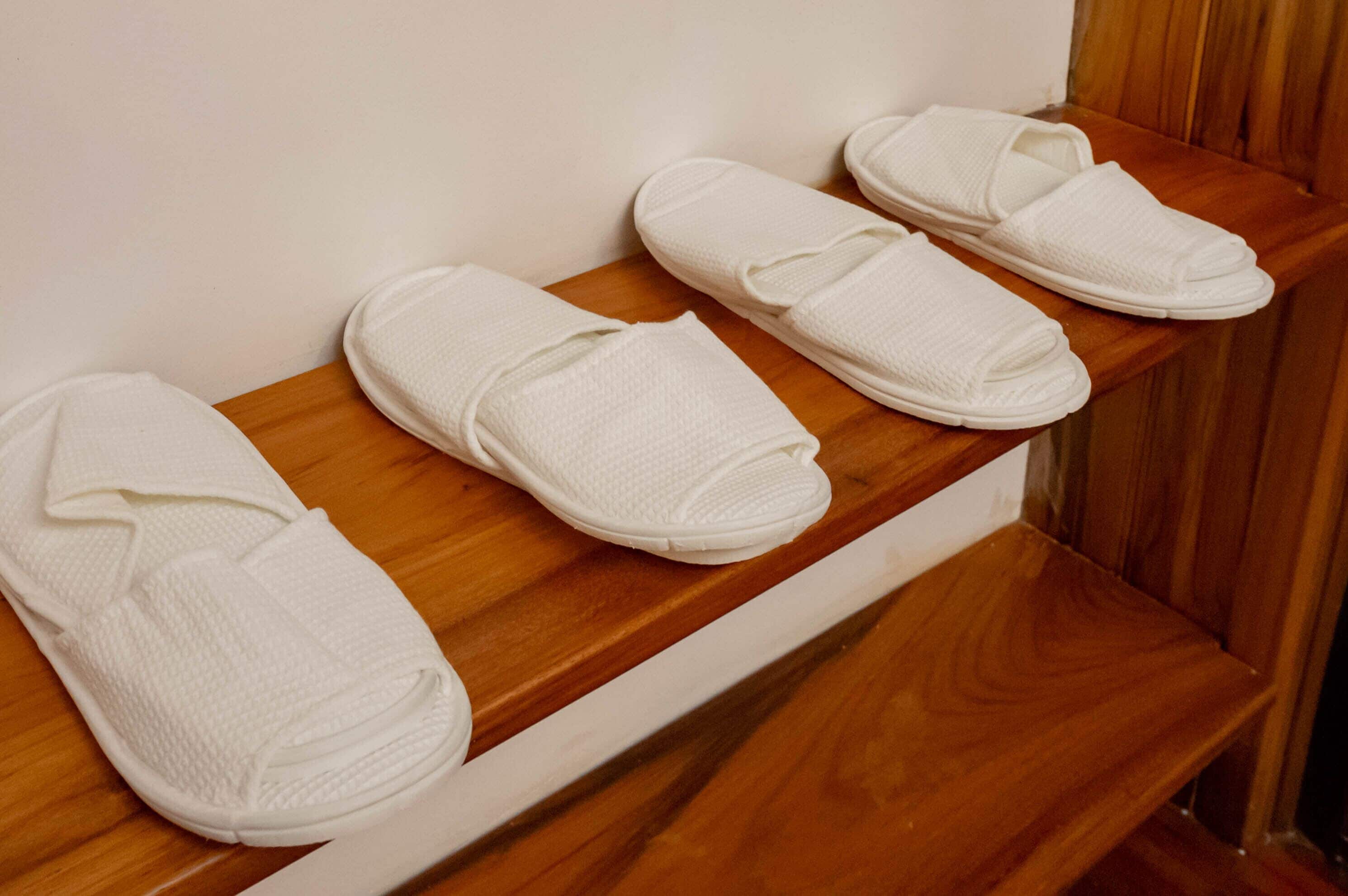 Een houten bankje met netjes opgerolde witte pantoffels.