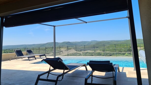 A rooftop pool area with lounge chairs and a view of green hills. - Villa Indépendante - Piscine Privée - Clim - Vue Exceptionnelle (Orgnac l'Aven)