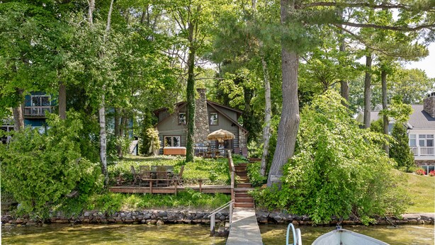 Une maison avec une cheminée en pierre, un quai et un bateau.