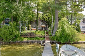 Une maison avec une cheminée en pierre, un quai et un bateau.