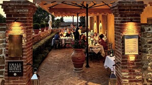 Un área de comedor al aire libre con muros de ladrillo, un patio cubierto y piso de ladrillo.