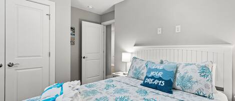 A bedroom with a bed, white walls, and a door.