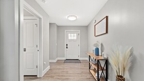 A hallway with a wooden floor, white walls, and a door at the end. - Family Friendly! 3bd, 2BA Home! Close to Beach! HOT Tub! (Panama City Beach)