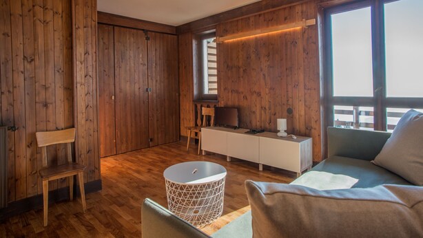 A room with wooden walls, a sofa, a chair, a small table, and a TV. - Vacation Home Myrtle Bielmonte (piatto)