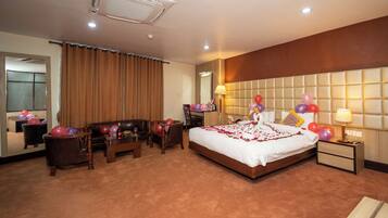 A hotel room with a large bed, a wooden headboard, a bedside table, a nightstand, a chair, a desk, and a mirror.
