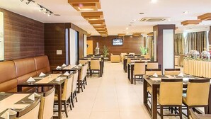 Een restaurant met lange tafels en ruimtes, een televisiescherm en een houten wand.