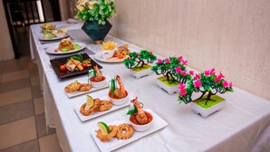 A buffet table with various dishes and a decorative bonsai tree. - Dees Hotels (Lagos)