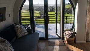 Una habitación con un gran ventanal arqueado, un sofá y vistas a un paisaje verde.