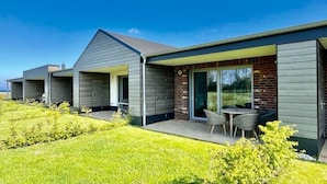 Uma casa moderna com varanda coberta e área de refeições.