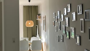 Um corredor com área de jantar, quadros nas paredes e luminária no teto.