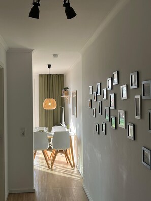 Un couloir avec un coin repas, des tableaux encadrés au mur et un luminaire au plafond.