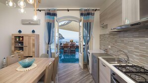 Een compacte keuken met uitzicht op een balkon, een eethoek met tafel en stoelen, en een wasmachine.