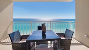 A balcony with a table and chairs, overlooking a clear blue sea.