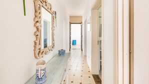 A hallway with a wooden bench, a mirror, and a blue trash bin. - 3315 Villetta Carmela by Barbarhouse (Alliste)