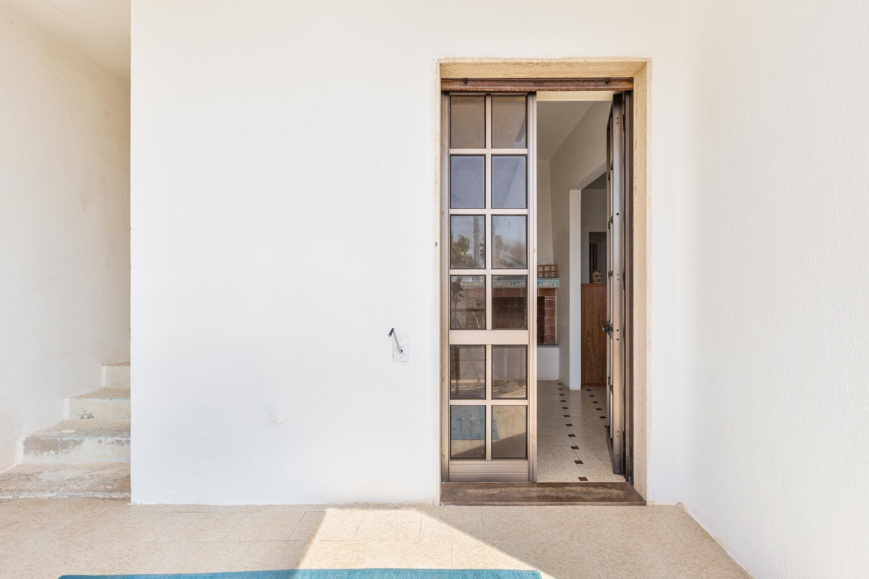 A doorway leading to a hallway with a tiled floor and a wooden door.