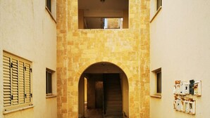A narrow stone-paved courtyard with a central archway leading to a second-floor balcony. - Escape and Relax Apartment (Mandria)
