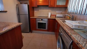 A kitchen with wooden cabinets, a stainless steel refrigerator, an oven, a dishwasher, and a granite countertop. - Escape and Relax Apartment (Mandria)