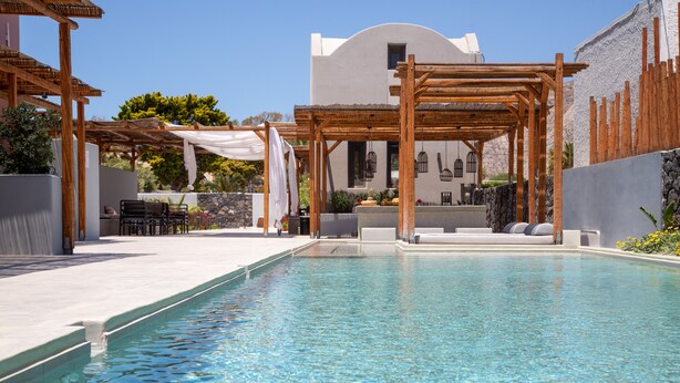 A swimming pool with a wooden pergola and outdoor seating area.