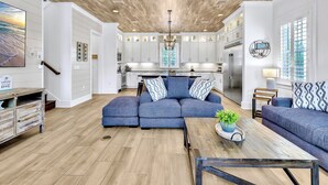 Un salón amplio con un sofá azul, una mesa de centro y piso de madera.