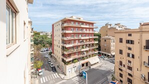 Un edificio de varios pisos con balcones, un paso de peatones y coches estacionados.