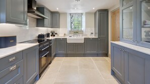 A modern kitchen with grey cabinetry, a large window, and a built-in oven. - Brontë Cottage  -  3 Bedroom Riverside Cottage. Sedbergh 4 Miles. (Garsdale)