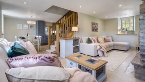 A cozy living room with a sofa, a coffee table, and a dining area with a table and chairs. - Brontë Cottage  -  3 Bedroom Riverside Cottage. Sedbergh 4 Miles. (Garsdale)