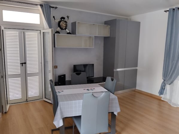 Una habitación compacta con una mesa de comedor, sillas, un televisor y armarios empotrados.