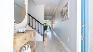 A hallway with a wooden console table, a mirror, and a staircase with black railings. - Cozy home Near Disney Free resort Access 4463 (Kissimmee)