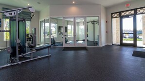 A gym with exercise equipment, a mirrored wall, and an exit door. - Cozy home Near Disney Free resort Access 4463 (Kissimmee)