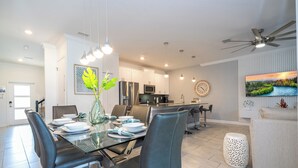A modern dining area with a glass table, black chairs, and a decorative plant. - Cozy home Near Disney Free resort Access 4463 (Kissimmee)