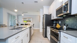 A modern kitchen with white cabinetry, stainless steel appliances, and a central island. - Cozy home Near Disney Free resort Access 4463 (Kissimmee)