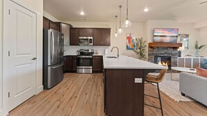 Una cocina moderna con electrodomésticos de acero inoxidable, una isla central y una chimenea de piedra.