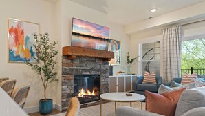 Una sala de estar con chimenea de piedra, un sofá, una mesa de centro y vistas al exterior.