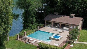 Una casa con piscina, mobiliario de patio y vista al lago.