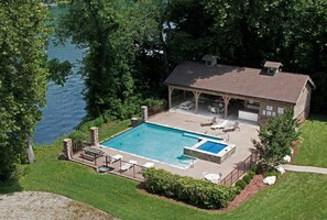 Una casa con piscina, muebles de patio y vista a un lago.