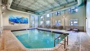 An indoor swimming pool with a mural, lounge area, and large windows.