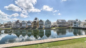 Een rij herenhuis aan het water, met een houten steiger en een rustig meer dat de gebouwen weerspiegelt.