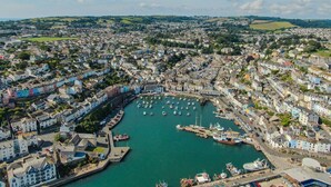 Une ville côtière dotée d’un port de plaisance rempli de bateaux, de bâtiments aux couleurs vives et d’un mélange de bâtiments résidentiels et commerciaux.