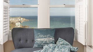 Ein Zimmer mit Blick auf eine Küstenstadt durch große Fenster.