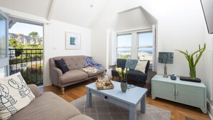 Ein großzügiges Wohnzimmer mit hohen Decken, einer Couch, einem Couchtisch und Meerblick durch große Fenster.